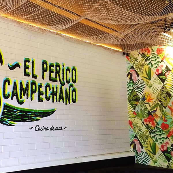 A restaurant with a mural on the wall that says "El Perro Campanano" - vibrant artwork enhances the dining experience
